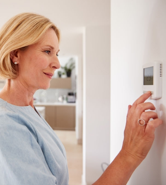 a woman changing a temperature in a thermostat