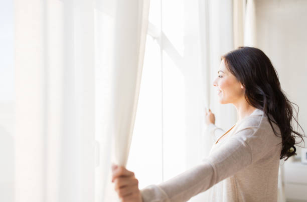 Close up of woman opening window curtains