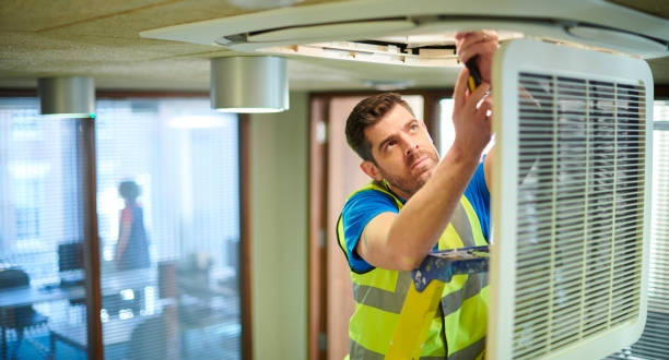 air con technician in an office checking a ducted system
